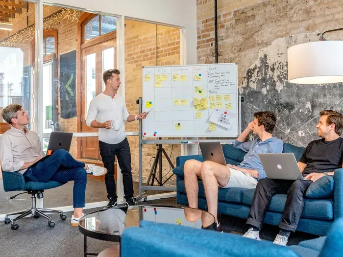 Team meeting in a casual office with laptops and whiteboard, showing how CityBiz Spot helps grow a local business